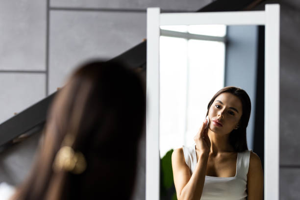 istock Young beautiful woman using applying cream softening moisturizer with cotton pad on her face, removing cosmetics. Beauty treatment, skin body care. 1454394356