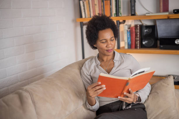 istock Woman reading book at home 1454395991