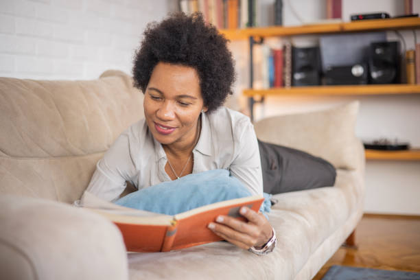 istock Woman reading book at home 1454396002