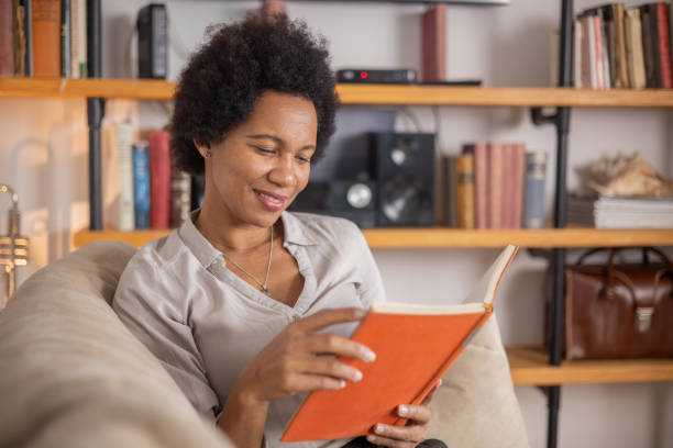 istock Woman reading book at home 1454396004
