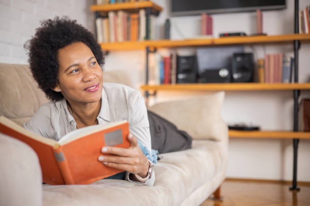 istock Woman reading book at home 1454396008