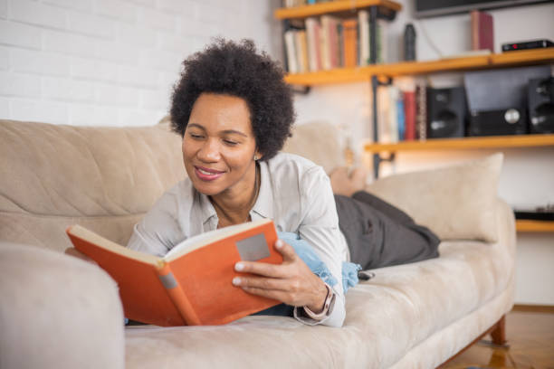 istock Happy woman relaxing and reading a book 1454396012