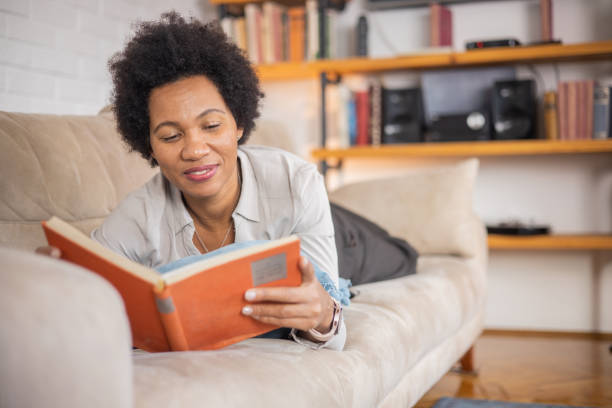 istock Happy woman relaxing and reading a book 1454396023