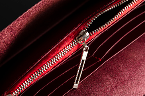 An open zipper on a red leather item or wallet.