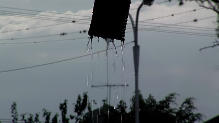 Silhouette of Water Pipe Dripping Water on the Street at Sunset. Close Up.