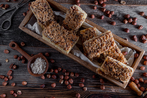 Delicious homemade hazelnut sponge cake with crunchy hazelnut topping. Served sliced on dark wooden background with ingredients. Closeup and flat lay with space for text
