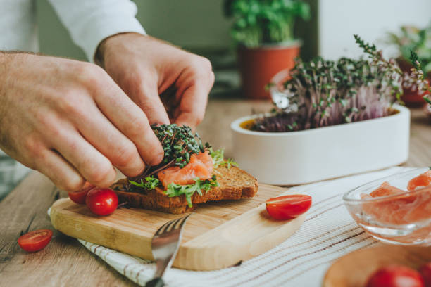 istock Man making sandwich with salmon fish, microgreen and tomato 1454397021