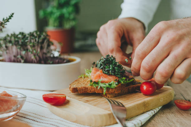 istock Man making sandwich with salmon fish, microgreen and tomato 1454397034