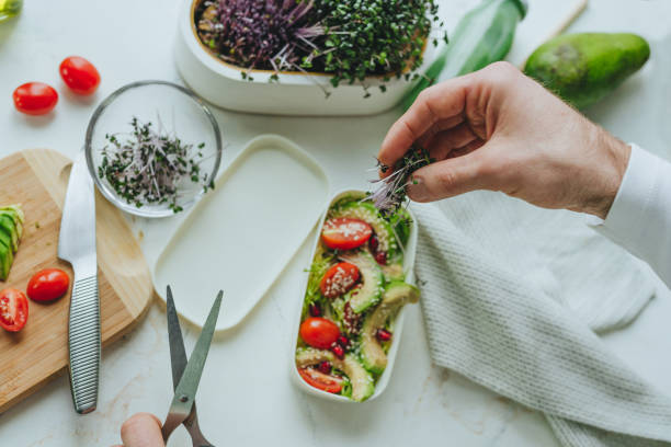 istock Males hands cooking salad in lunchbox with avocado, radish microgreen sprouts 1454397673