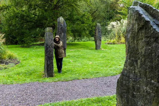 Photo of A tourist trying to communicate through the Seven Sister Stone Circle, Blarney Castle, Ireland.