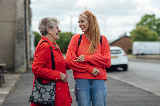 I Love You Grandma A young woman standing outdoors arm and arm with her grandma outdoors on a path in Newcastle Upon Tyne, England while enjoying a day out together. They are looking at each other and laughing. doing a favor stock pictures, royalty-free photos & images