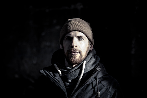 dark style portrait of a man wearing cap.