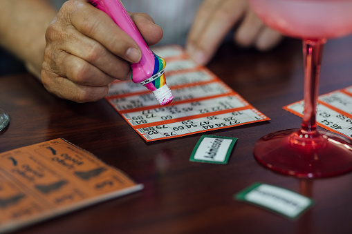 An unrecognisable man playing bingo at a social club in Newcastle upon Tyne, England. He is marking the numbers off his sheet with a dabber.