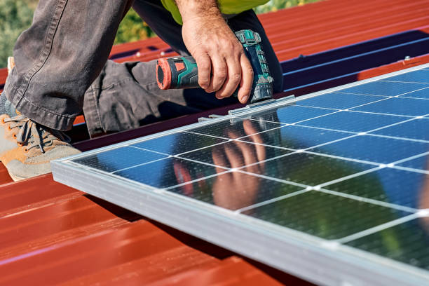 家の屋上にスタンドアロンの太陽光発電ソーラーパネルシステムを設置するドリルを持つ男性の手。代替エネルギー、再生可能エネルギー源、電力持続可能な資源のコンセプト。 - standalone ストックフォトと画像