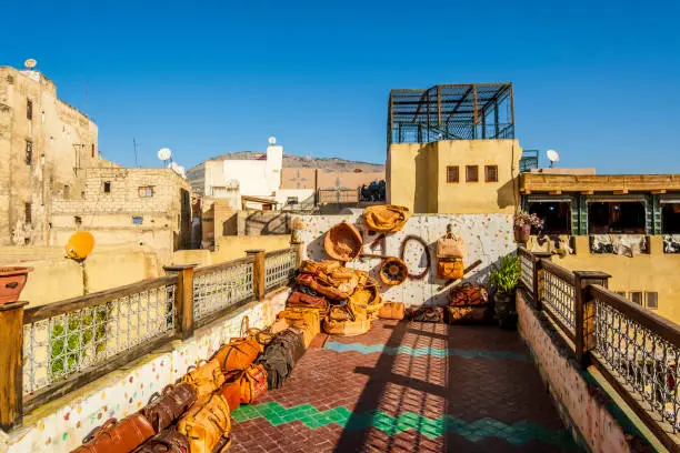 Variety of leather bags and pouffes exposed for sale on a terrace with a tannery view in Fes, Morocco, North Africa