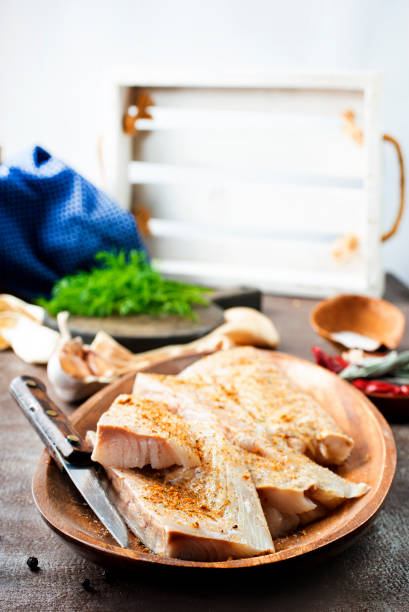 istock Fresh raw fish fillet with spices, pepper, salt, basil on a stone plate, top view, square 1454405227