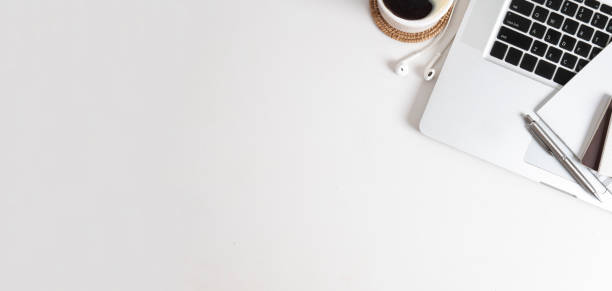 istock Laptop, notebook, coffee cup and earphone on white working desk Top view with empty copy space. 1454405467