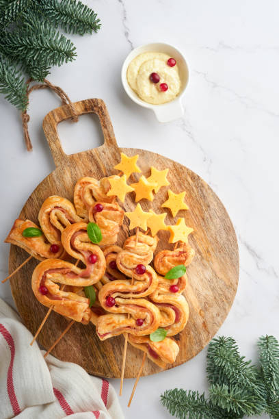 Christmas or New Year appetizer. Christmas tree shape puff pastry buns with cheese and ham. Group of Christmas tree shapes on wooden board. Festive idea for Christmas or New Year dinner. Top view. Christmas or New Year appetizer. Christmas tree shape puff pastry buns with cheese and ham. Group of Christmas tree shapes on wooden board. Festive idea for Christmas or New Year dinner. Top view. twisted bacon stock pictures, royalty-free photos & images