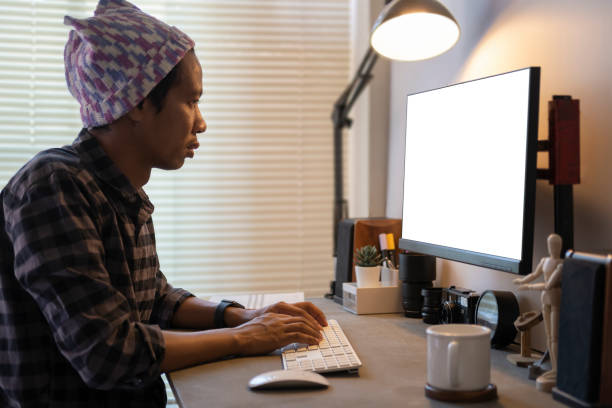 Side view of creative male freelancer working on design project with laptop in home office.