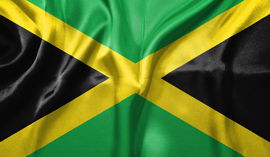 Jamaica flag wave close up. Full page Jamaica flying flag. Highly detailed realistic 3D rendering.