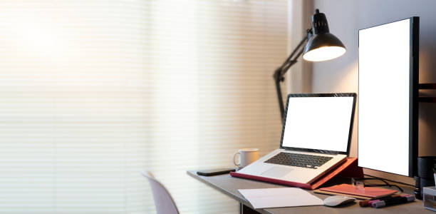 istock Bright modern laptop and supplies, white blank computer screen for your advertise design. 1454408344