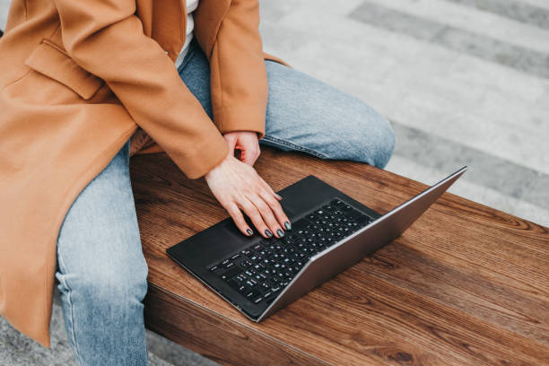 gros plan d’une femme tapant un ordinateur portable dans la rue sur le fond d’un immeuble de bureaux. femme d’affaires à distance de travail. haut de page wiew - top wiew photos et images de collection