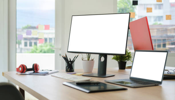 istock Modern workplace with white blank computer screen, laptop and graphic tablet on wooden table. 1454408743