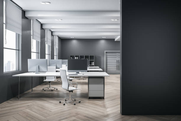 istock Front view on blank dark wall with place for advertising poster in open space office with city view from windows and modern computers on white tables and wooden parquet floor. 3D rendering, mockup 1454410349