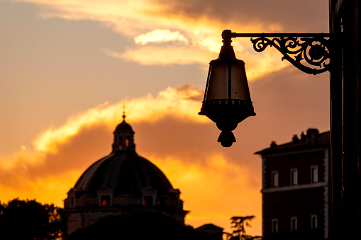 Silhouette of a roman street lamp in front of the dome of Santa Maria di Loreto, Rome, Italy