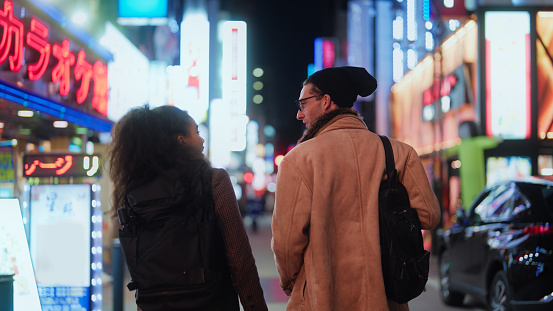Multi-racial tourist friends are walking in streets and exploring town in Tokyo at night