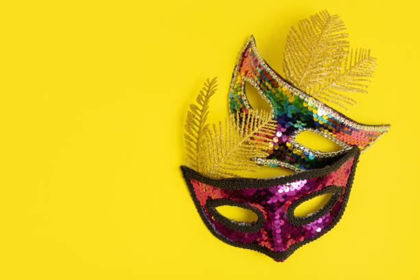 istock Two festive face mask for carnival celebration on colored background. Carnival flat lay concept 1454414667