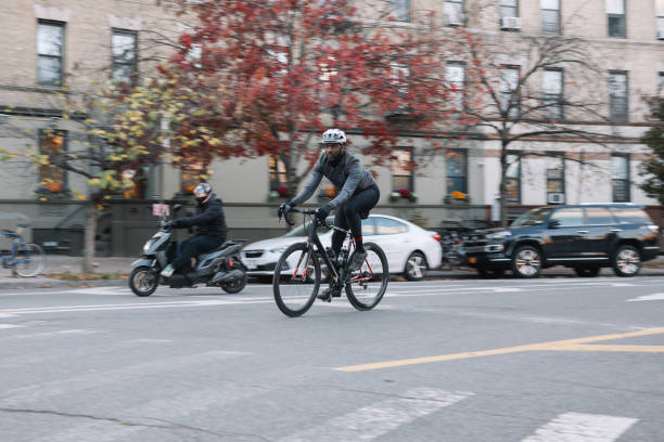 Black male cyclist riding through Brooklyn, New York. He is wearing cycling gear, going for a training ride or commuting in style, on a sunny Autumn day.