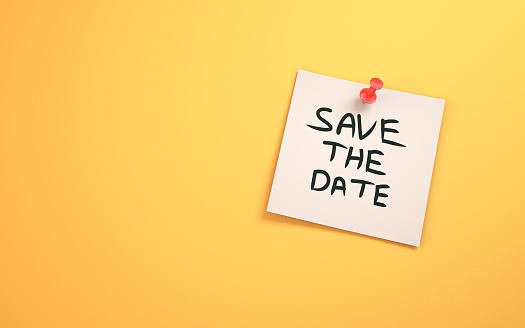 Save the Date Written on Note Paper Sitting on Yellow Background