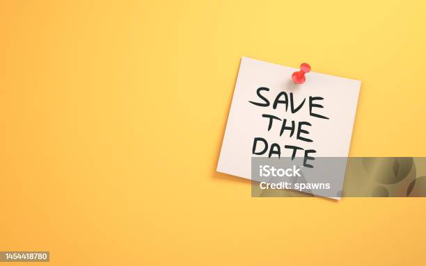 Save The Date Written On Note Paper Sitting On Yellow Background Stock Photo - Download Image Now