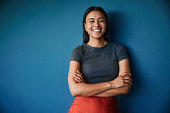 Young businesswoman smiling while standing against a blue backdrop