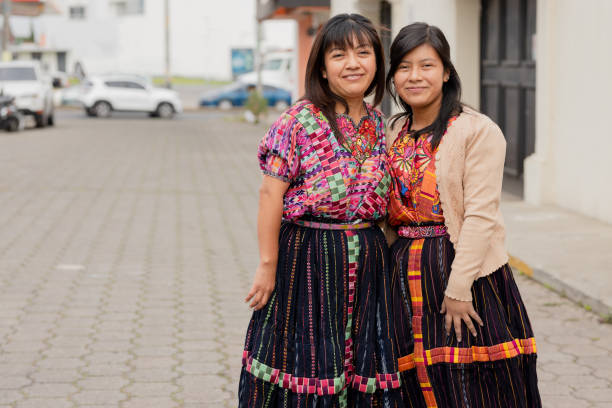 молодые женщины в типичном платье майя улыбаются в камеру - счастливые латиноамериканские сестры в деревне в латинской америке - guatemalan culture central america mother traditional culture стоковые фото и изображения