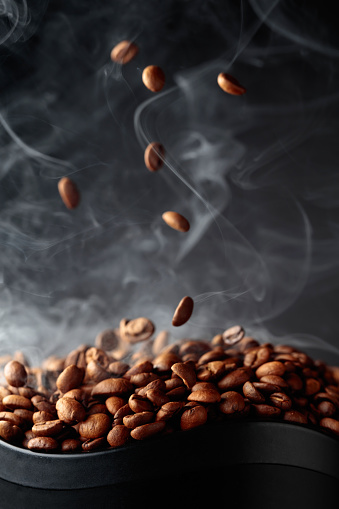 Steaming coffee beans in movement on a black background.