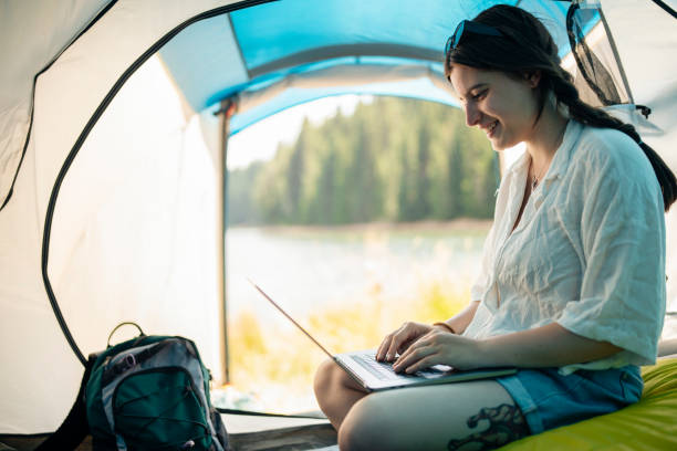 istock Young woman working with laptop during her camping vacation. 1454419201