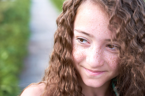 Cheerful freckled girl looking away, smiling, laughing. Close up of face. Cropped shot of teenage girl with dry spotted facial skin. Skincare, natural beauty, eye care, vision concept