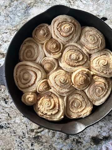 Homemade cinnamon rolls in a cast iron pan in a kitchen.