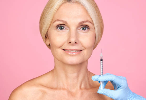 Smiling cute senior woman receiving lip injections. stock photo