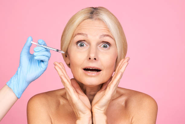 Excited senior woman before medical facial injection. stock photo