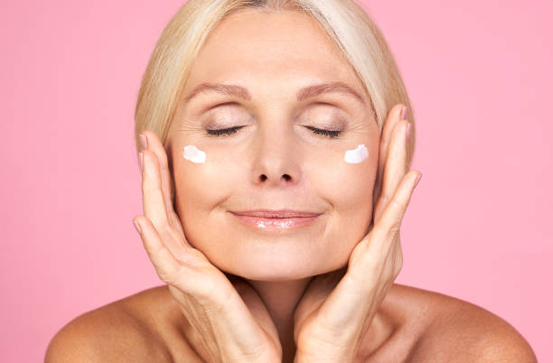 Charming mature lady with pleasure conducts procedures for the beauty of the face. stock photo