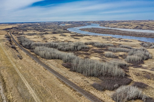 An aerial shot of a wide field and the South Saskatchewan River under the blue sky