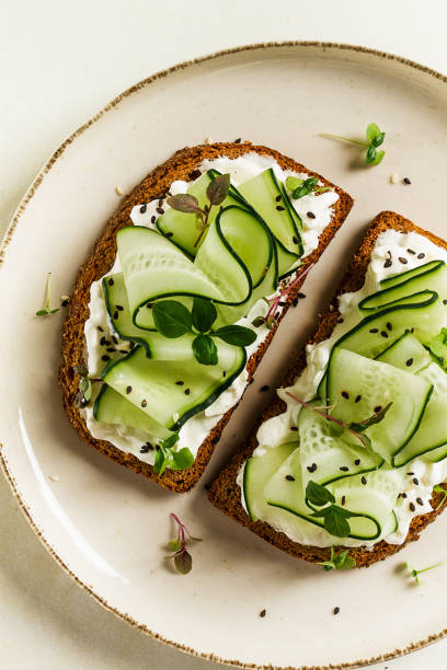 istock Breakfast, cereal bread sandwiches, cream cheese, sliced cucumber, with micro greenery on a light table, close-up, top view, selective focus, no people, 1454427087