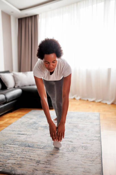 istock Fit woman doing warm up exercise during home workout 1454427186