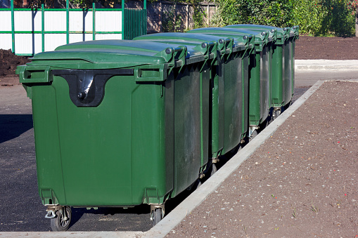 Colour coded bins for recycling, garden waste, glass and landfill in a shared lane behind houses in Glasgow, Scotland.