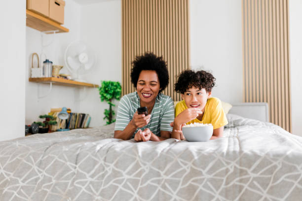 istock Mother and son watching TV and lying on bed 1454428498