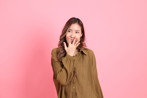 The young adult Asian woman with brown dressed standing on the pink background.