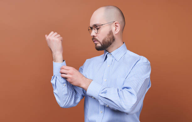 A businessman buttons a button on the sleeve of his shirt. stock photo